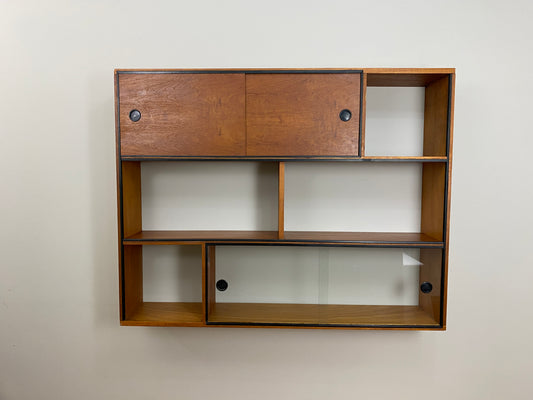 Wooden wall shelf with glass panels on a plain wall